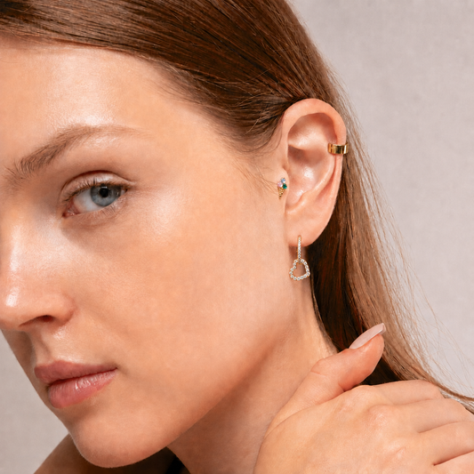 Goldfarbener Herzanhänger an einem Hoop am Ohr getragen